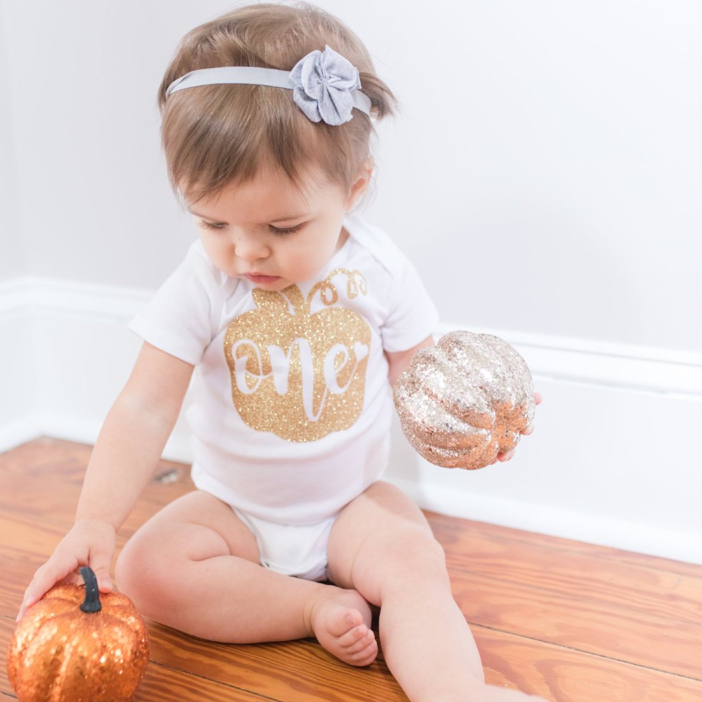cute little baby in a glitter pumpkin first birthday onesie